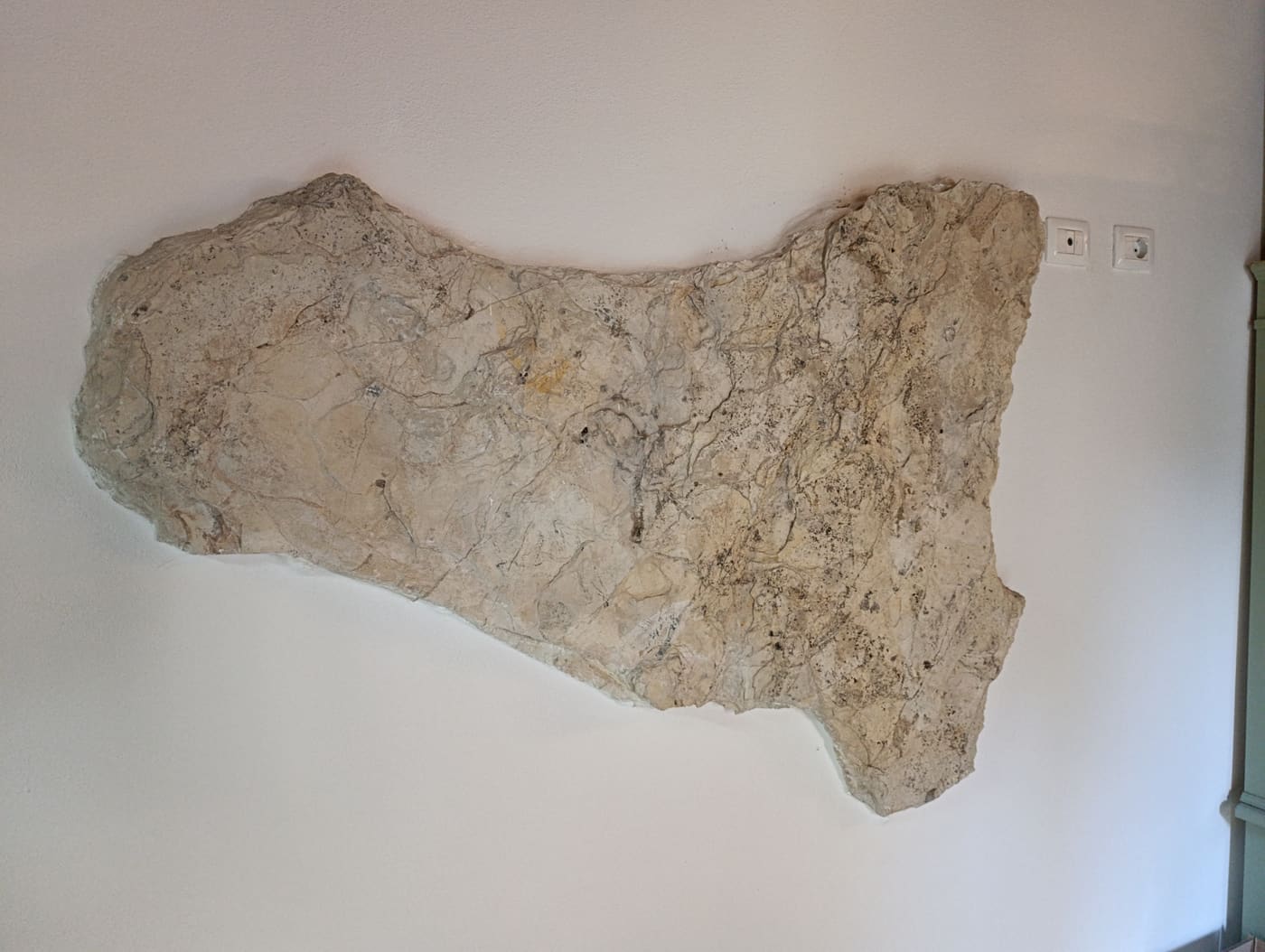 Grande lastra di pietra naturale sagomata a forma di Sicilia, appesa alla parete della sala
