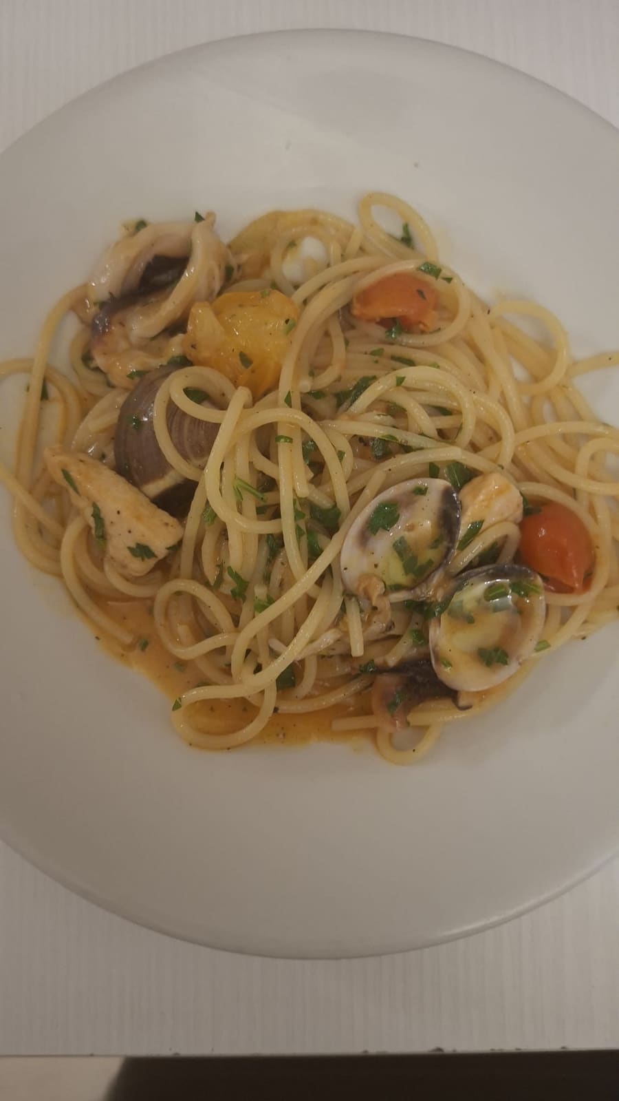 Spaghetti con vongole, calamari, pesce e pomodorini, con prezzemolo fresco