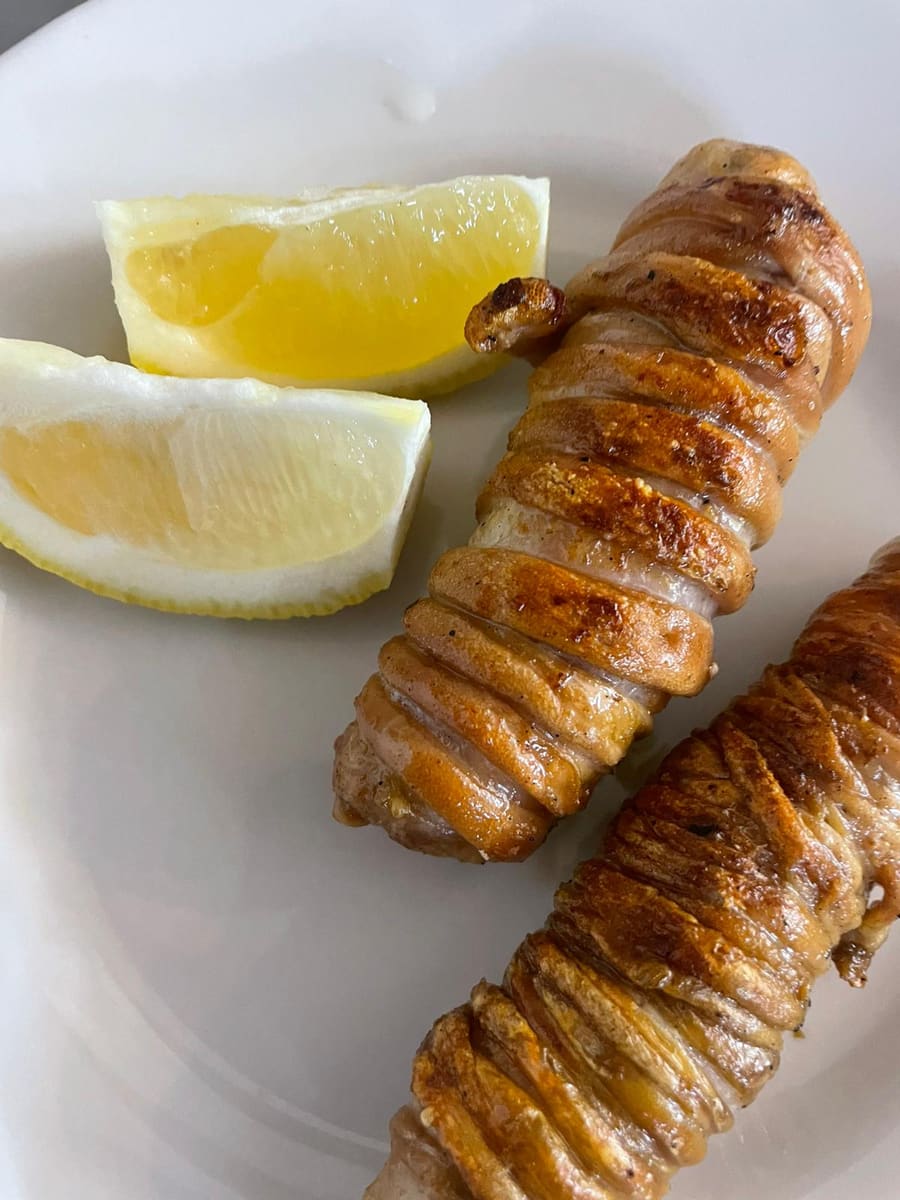 Stigliola, lo spiedino tipico siciliano arrotolato e arrostito, con spicchi di limone